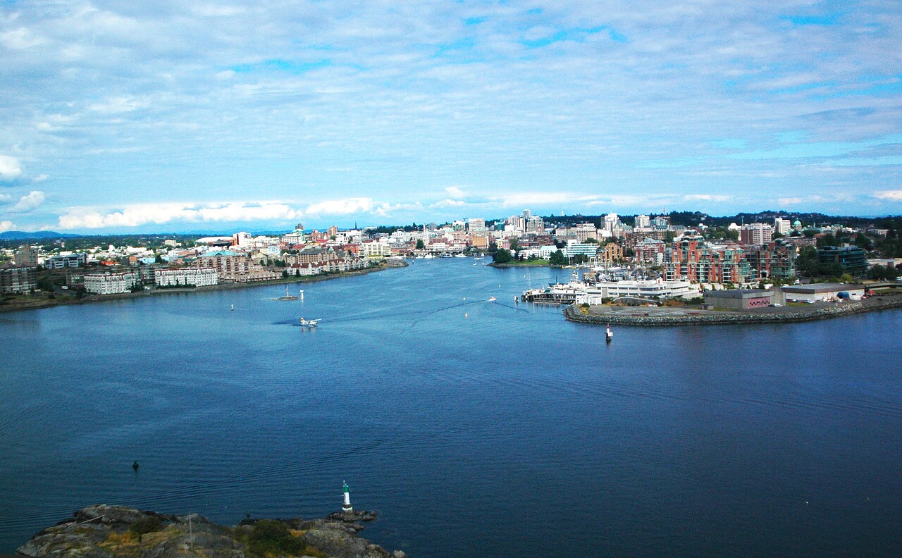Victoria harbour on Vancouver Island seen from above: open water, a seaplane landing, and the low city along both shores.